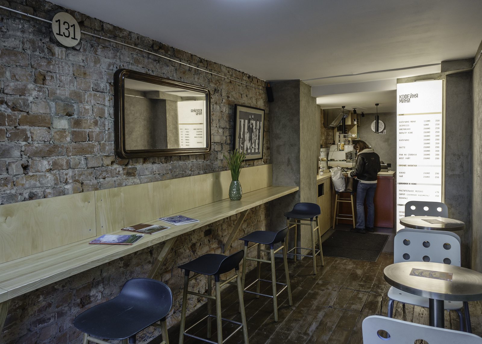 The narrow bar counter along the brick wall, with the menu board visible at the far end.