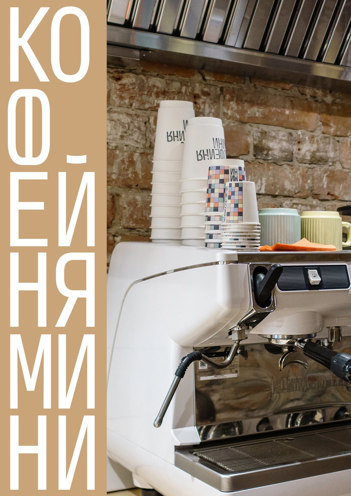 The wordmark on a tan band beside the espresso machine, branded cups stacked on top.