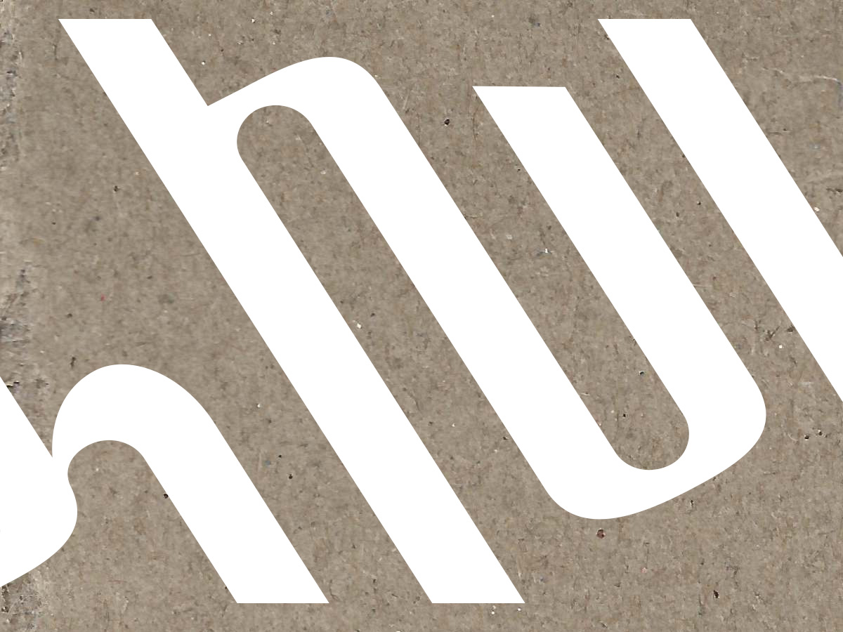 Close-up of the Dzakhlik wordmark—white left-leaning Armenian letterforms on a textured kraft-paper background.