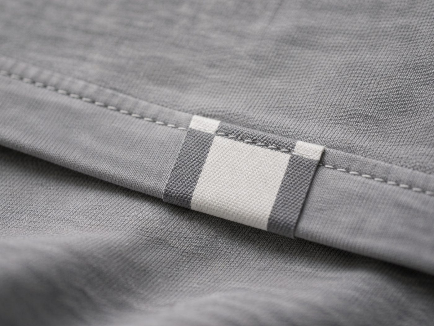 Close-up of a woven grid label sewn into the T-shirt's hem.
