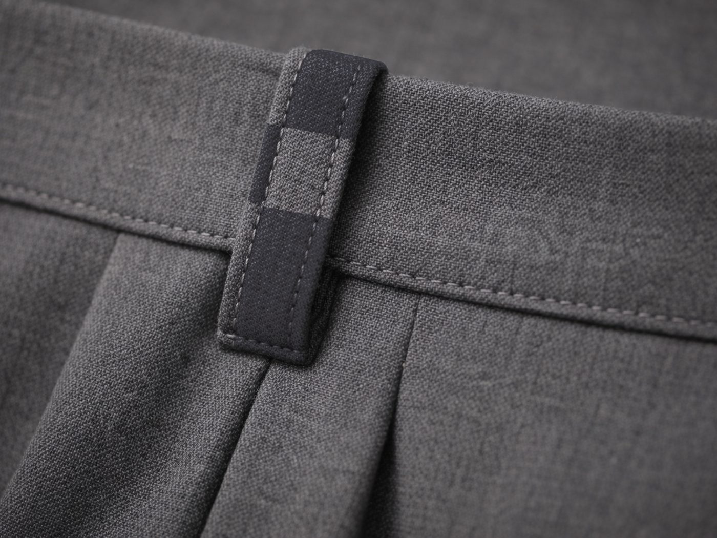 Close-up of the trousers' waistband tab, woven in the brand's checkerboard pattern.