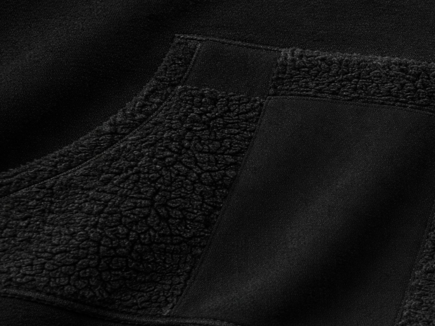 Close-up of the hoodie's pocket, mixing sherpa and smooth fleece panels along the grid.