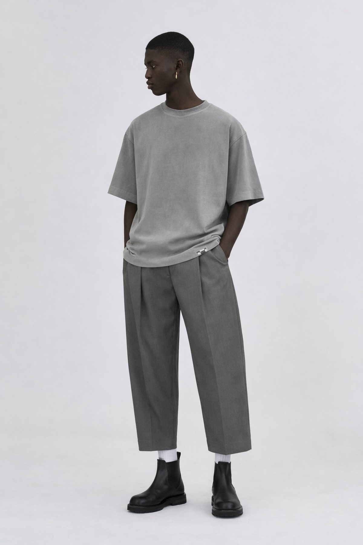 Model wearing an oversized grey T-shirt and wide cropped trousers from the Prostor capsule.